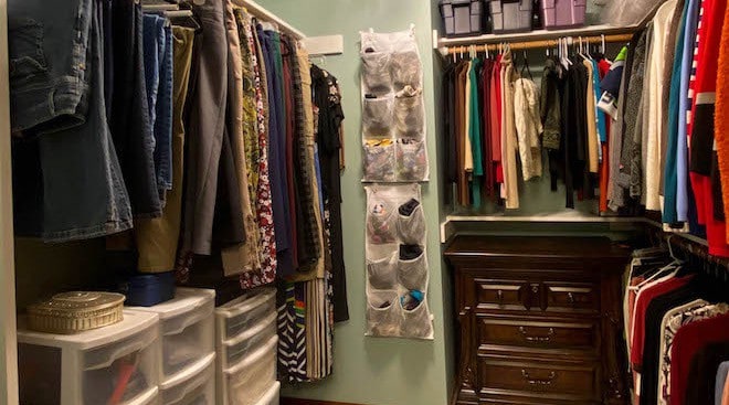 Well organized closet with chest drawers, clothes hanging.