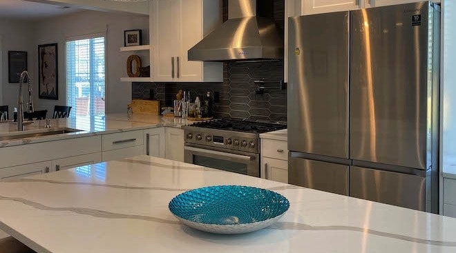Cabinets, kitchen island counter top with blue decorative bowl on top.
