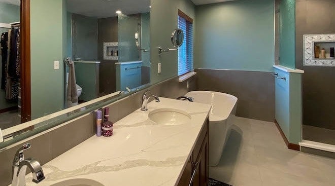 Bathroom countertop two sinks, bath tub, mirror, walk-in shower.