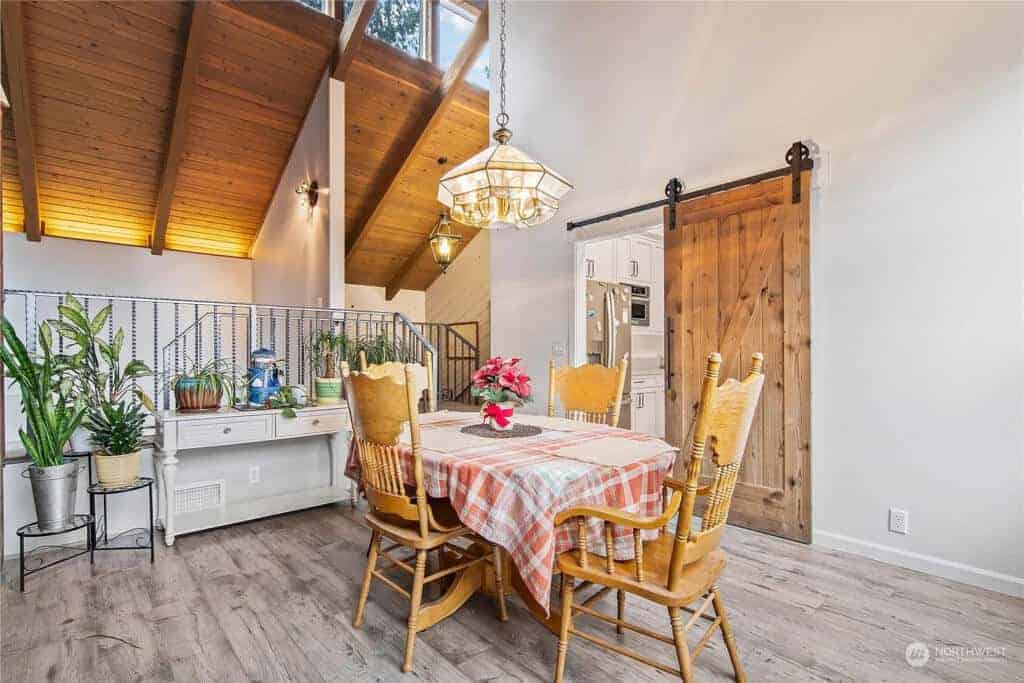 A frame dining room, wood floors, sliding barn door leading to kitchen.