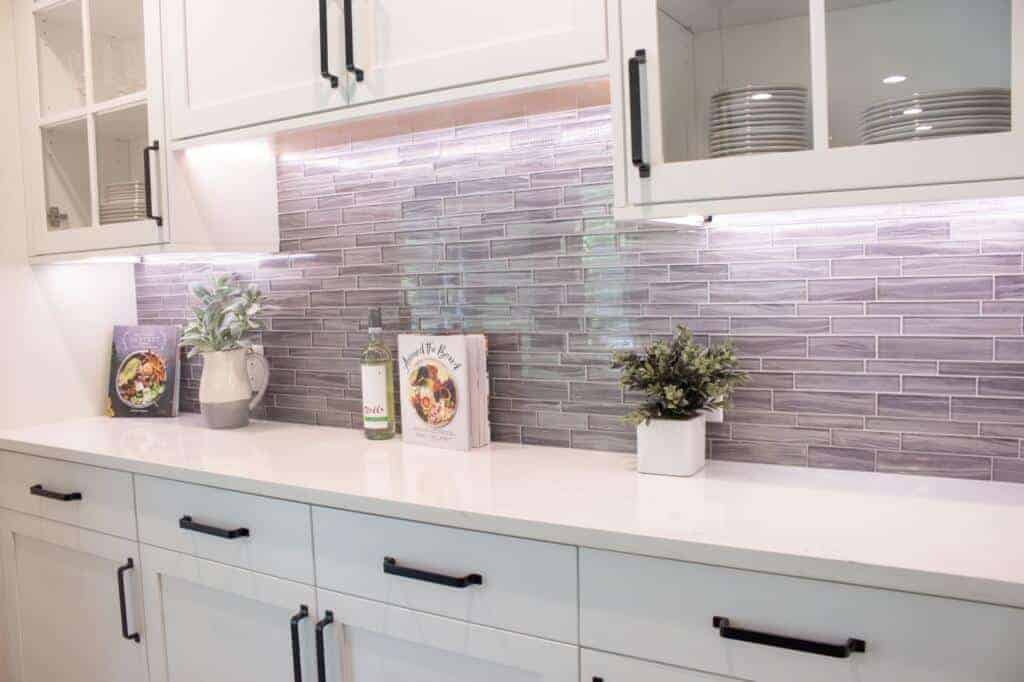 Kitchen wall tiles with white cabinets and drawers, Dishes and other nick-nacks.